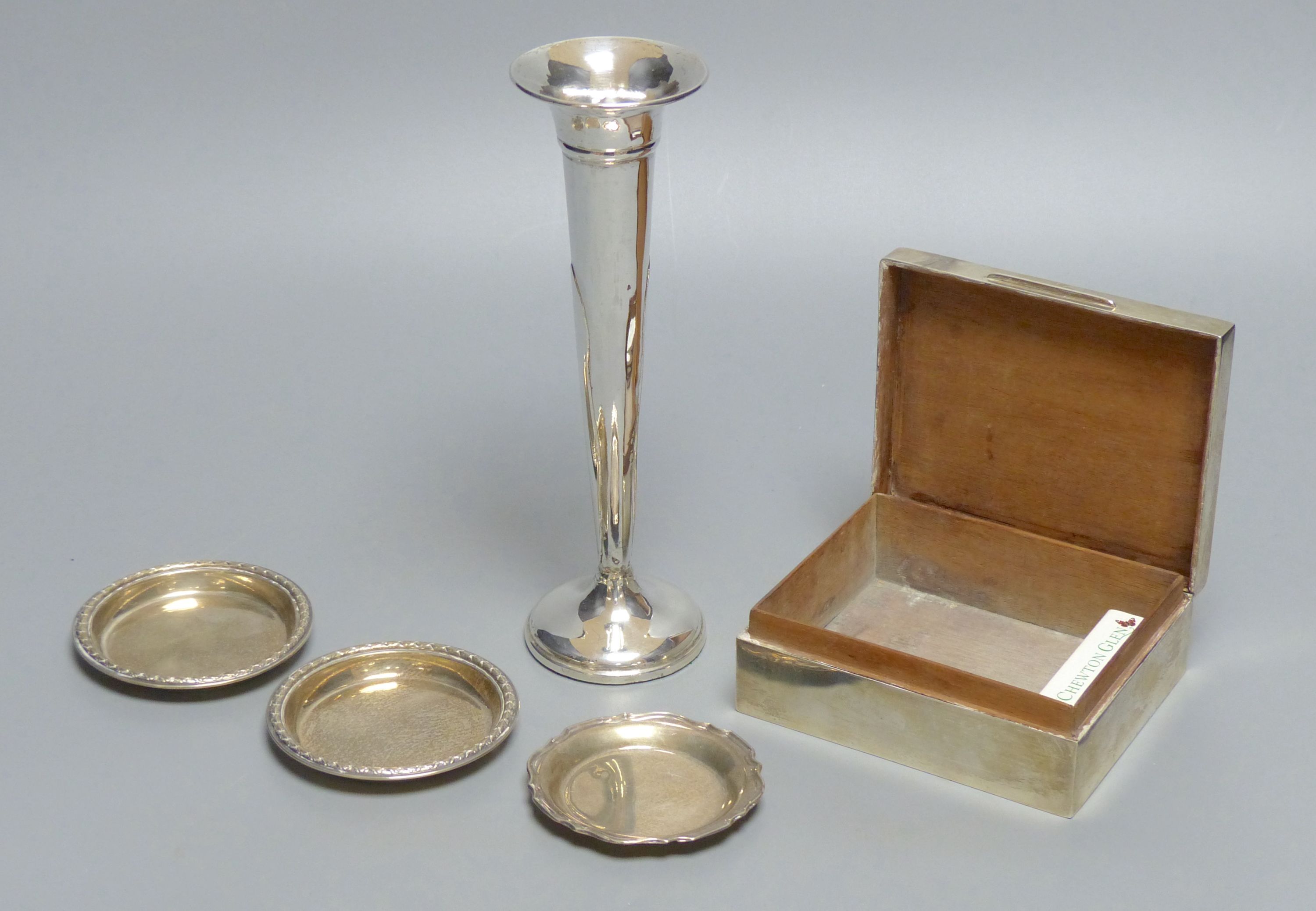 An engine-turned silver cigarette box, a pair of circular pin dishes, another pin dish and a specimen vase
